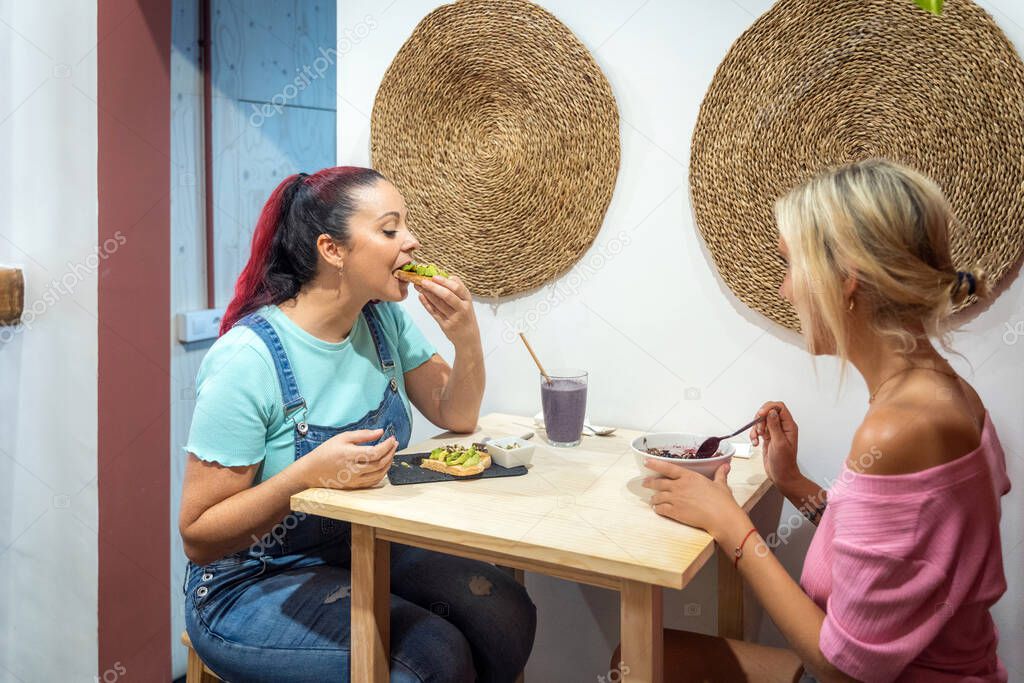 Young female friends having breakfast together in a restaurant. Friendship and food concept.