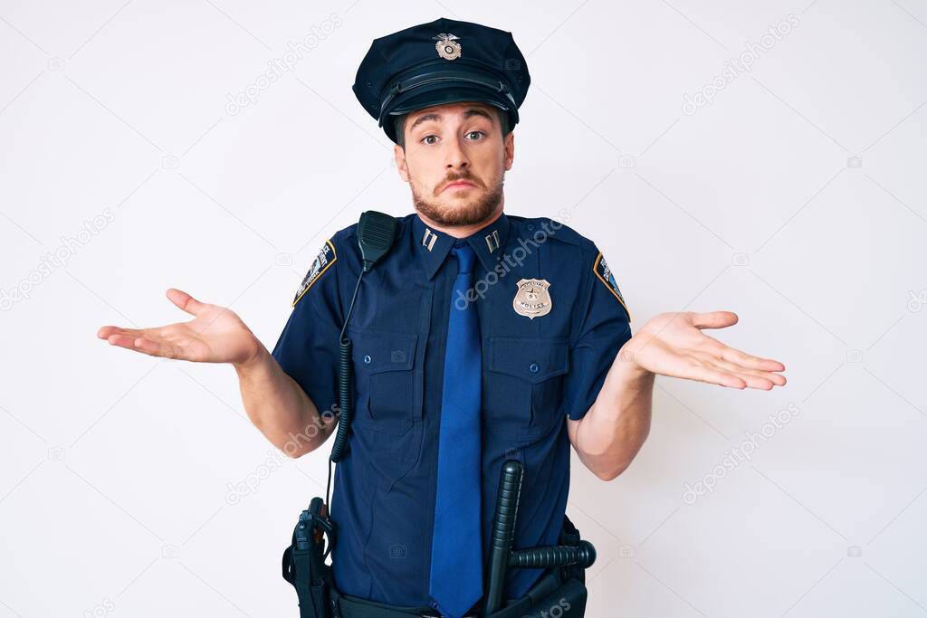 Young caucasian man wearing police uniform clueless and confused with open arms, no idea concept.