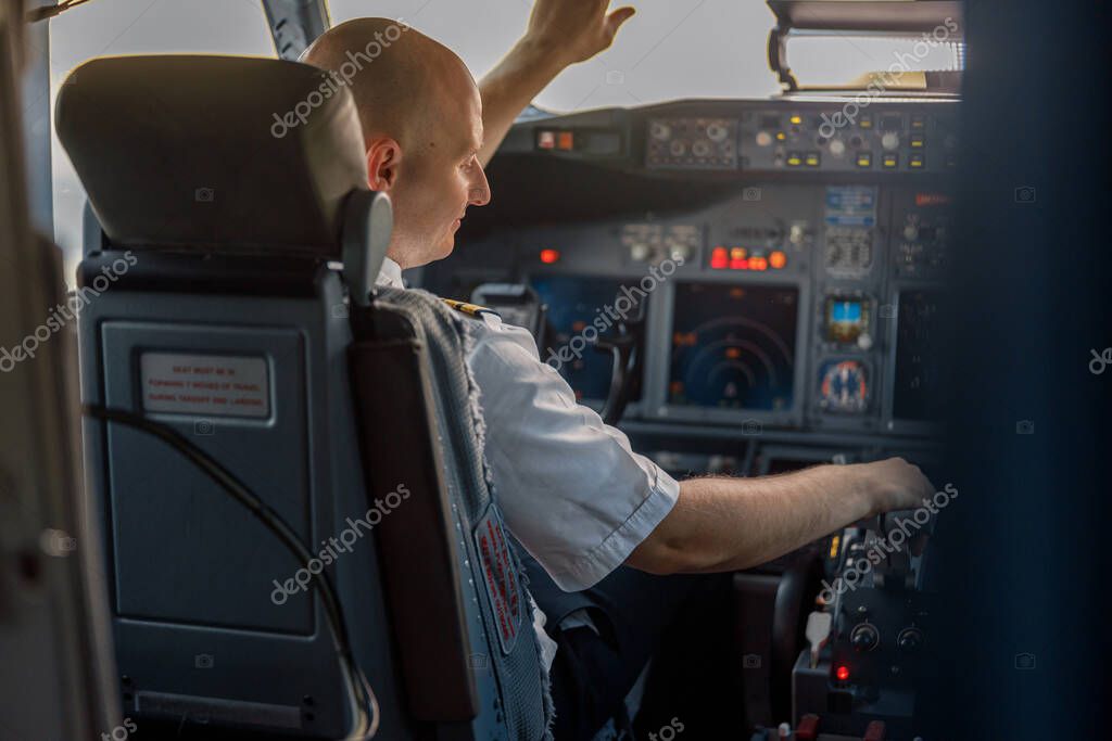 Focused professional pilot sitting in an airplane cabin, ready for takeoff. Aircraft, aircrew, occupation concept