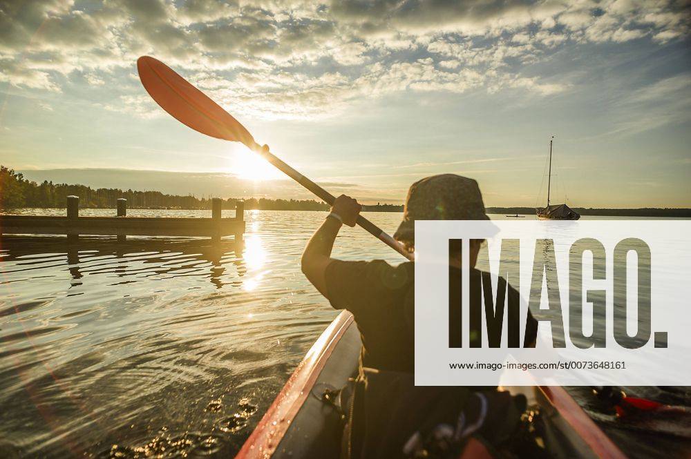 Eine Frau fährt mit ihrem Kajak auf dem Starnberger See dem Sonnenuntergang entgegenan, Starnberg, Bayern, Deutschland. Eine Frau paddelt auf einer Kajaktour auf dem Starnberger See