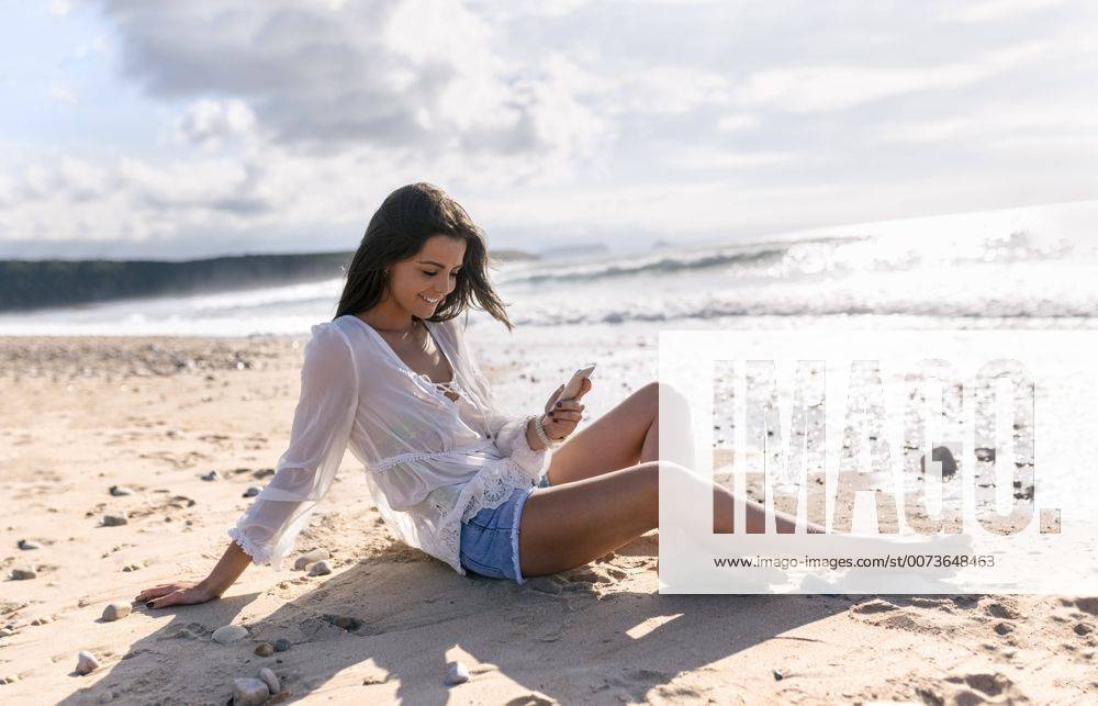 Youniverse - Young Holidays Spain, Asturias, beautiful young woman with smartphone on the beach model released Symbolfoto MGOF002209