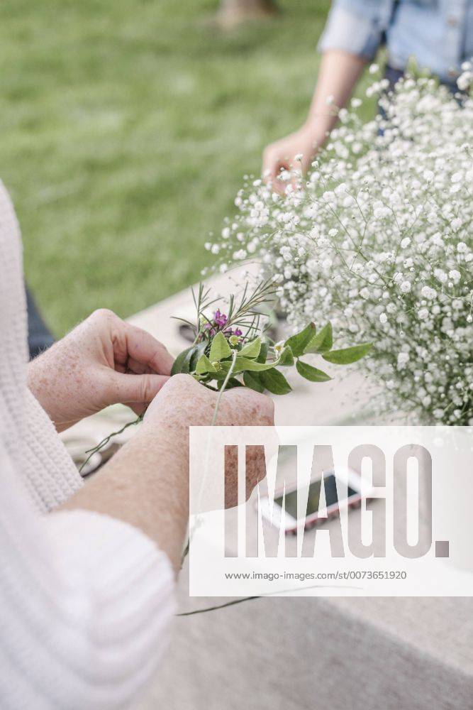 Close up of a woman, standing in a garden, making a flower wreath. Close up of a woman, standing in a garden, making a flower wreath. 22449