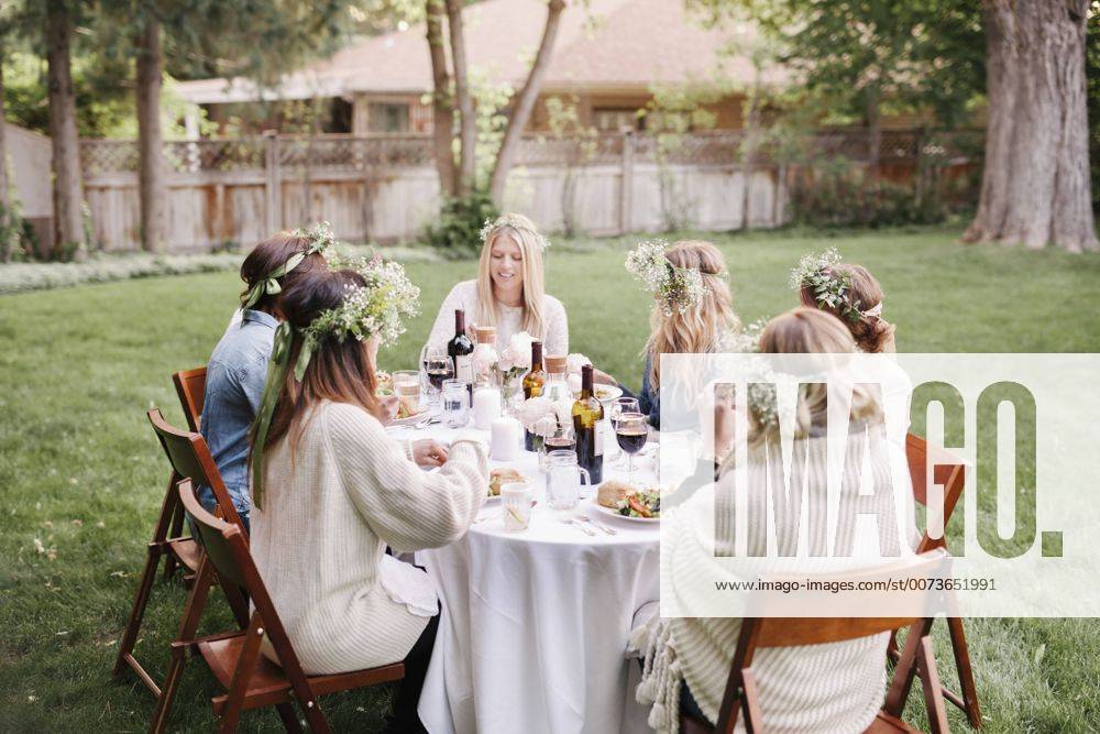 Group of female friends gathered around a table, in a garden, eating and drinking. Group of female friends gathered around a table, in a garden, eating and drinking. 22484