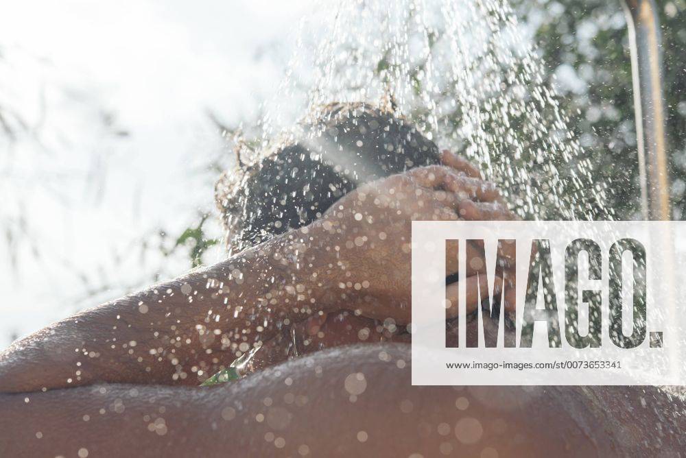 Back view of young man taking shower in garden model released Symbolfoto SKCF000180
