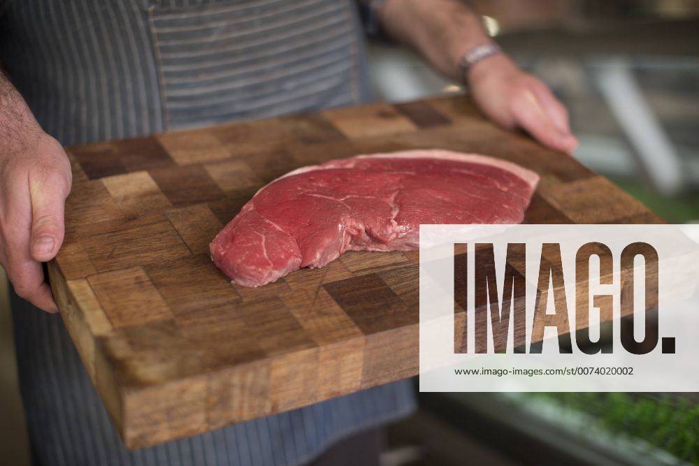Butcher holding raw steak on wooden board model released Symbolfoto property released ZEF010296