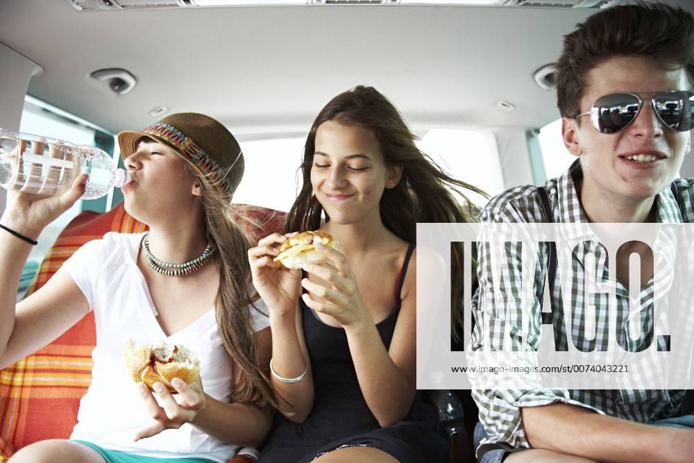 Three teenage friends having a snack in car model released Symbolfoto FSF00531