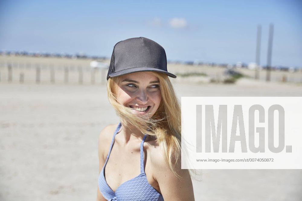 Youniverse - Young Holidays Happy young woman wearing baseball cap on the beach model released Symbolfoto SRYF000047
