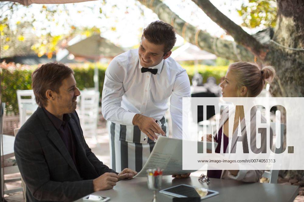 Waiter ready to serve couple seated at outdoor restaraunt model released Symbolfoto property released ZEF010255