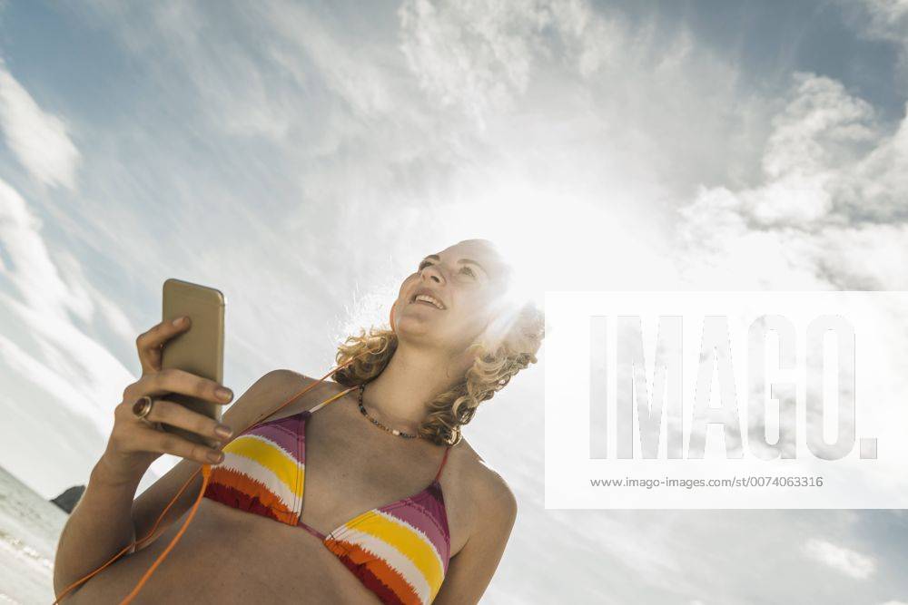 Youniverse - Young Holidays Teenage girl listening to music on the beach model released Symbolfoto UUF08402