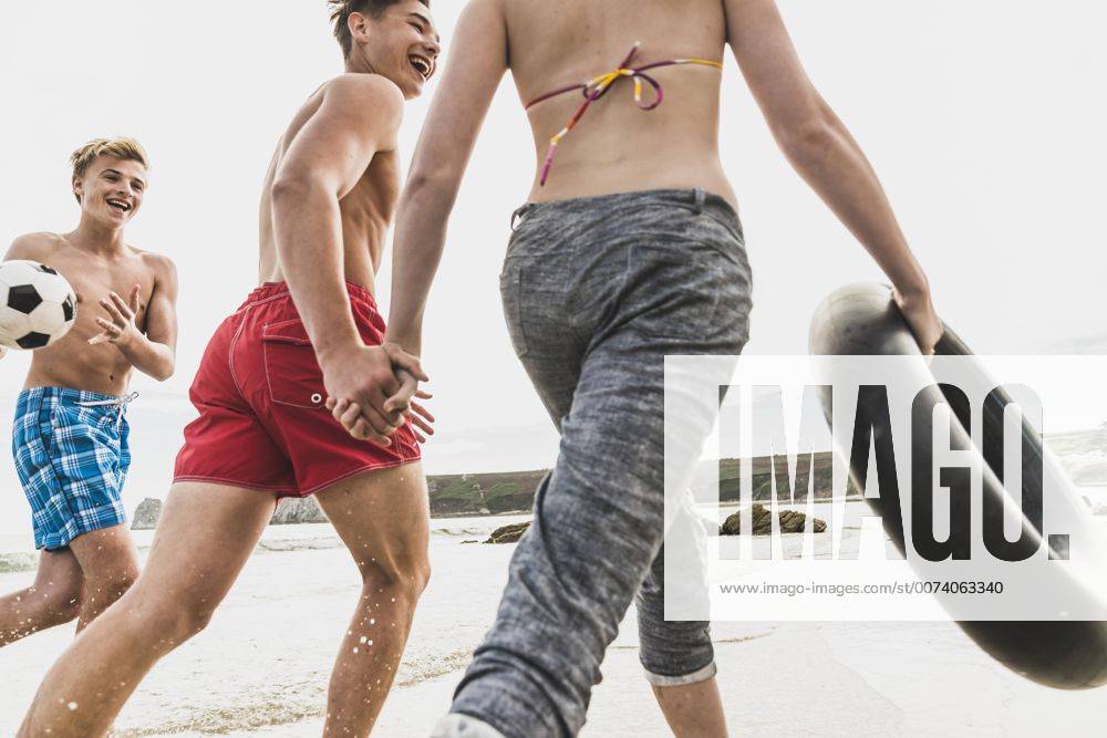Youniverse - Young Holidays Friends running with a ball and tyre on the beach model released Symbolfoto UUF08423