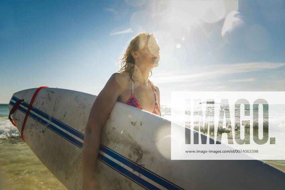 Youniverse - Young Holidays Teenage girl carrying surfboard at the sea model released Symbolfoto UUF08438