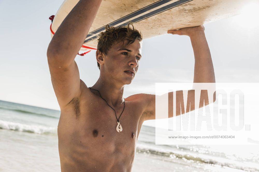 Youniverse - Young Holidays Teenage boy carrying surfboard at the sea model released Symbolfoto UUF08441
