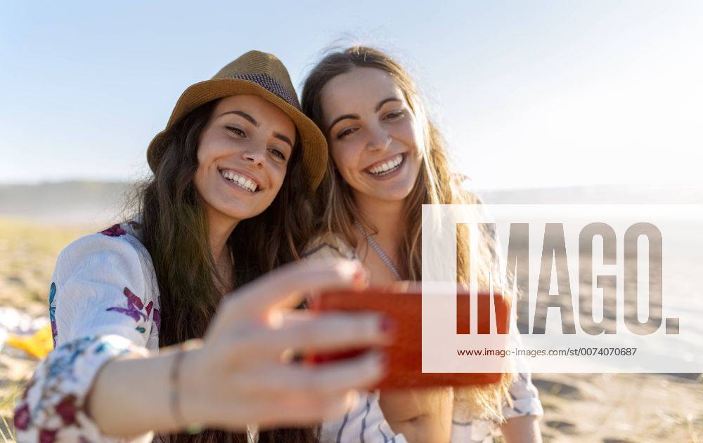 Youniverse - Young Holidays Two best friends taking selfie with smartphone on the beach model released Symbolfoto MGOF002431