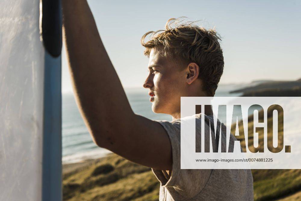Youniverse - Young Holidays Teenage boy with surfboard looking to the sea model released Symbolfoto UUF08755