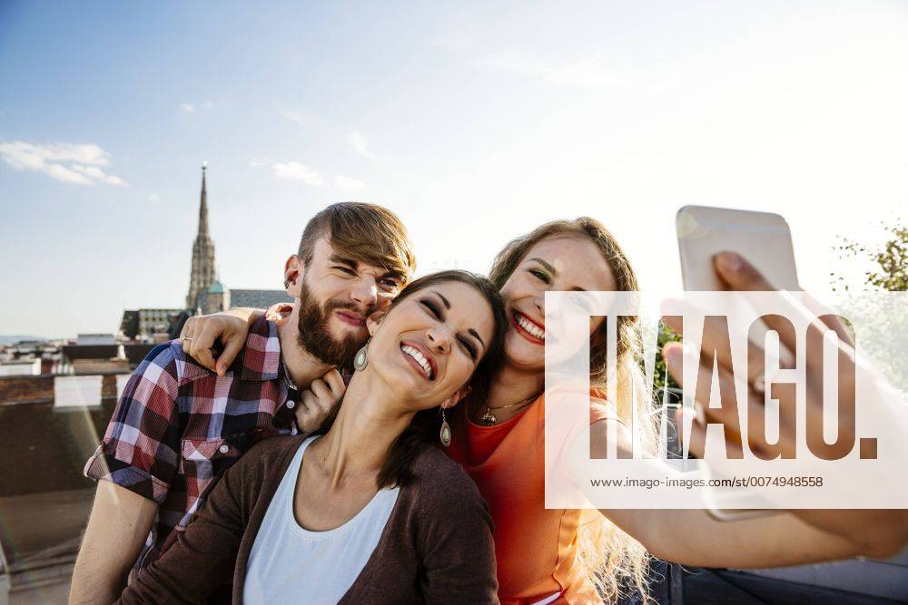 Youniverse - Young Holidays Austria, Vienna, three friends taking selfie on rooftop terrace with Stephansdom in the background model released Symbolfoto property released AIF00414