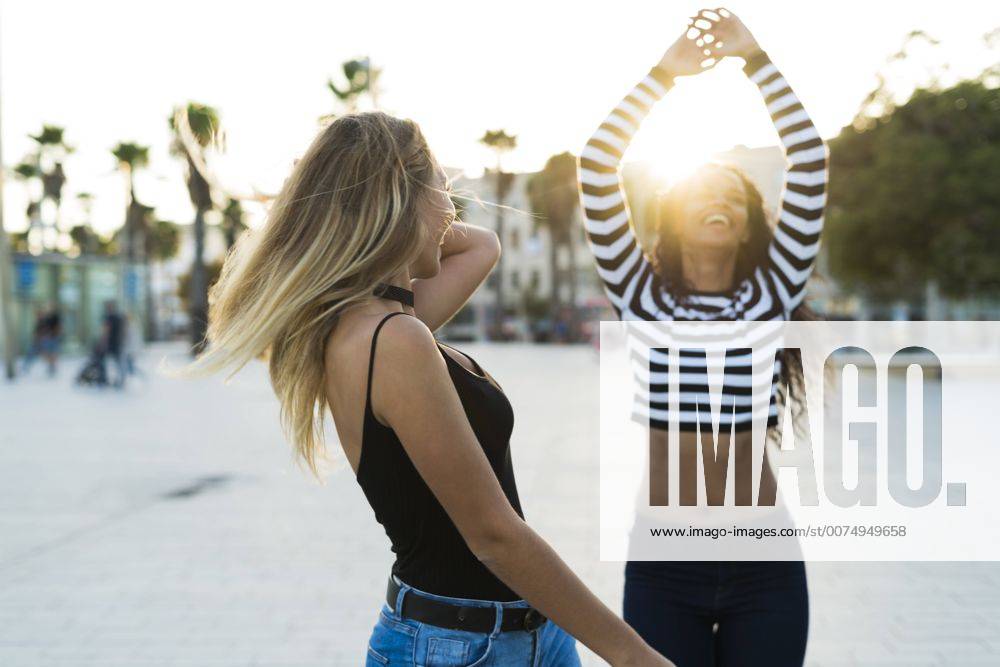 Youniverse - Young Holidays Two young women having fun on square at sunset model released Symbolfoto KKAF00013