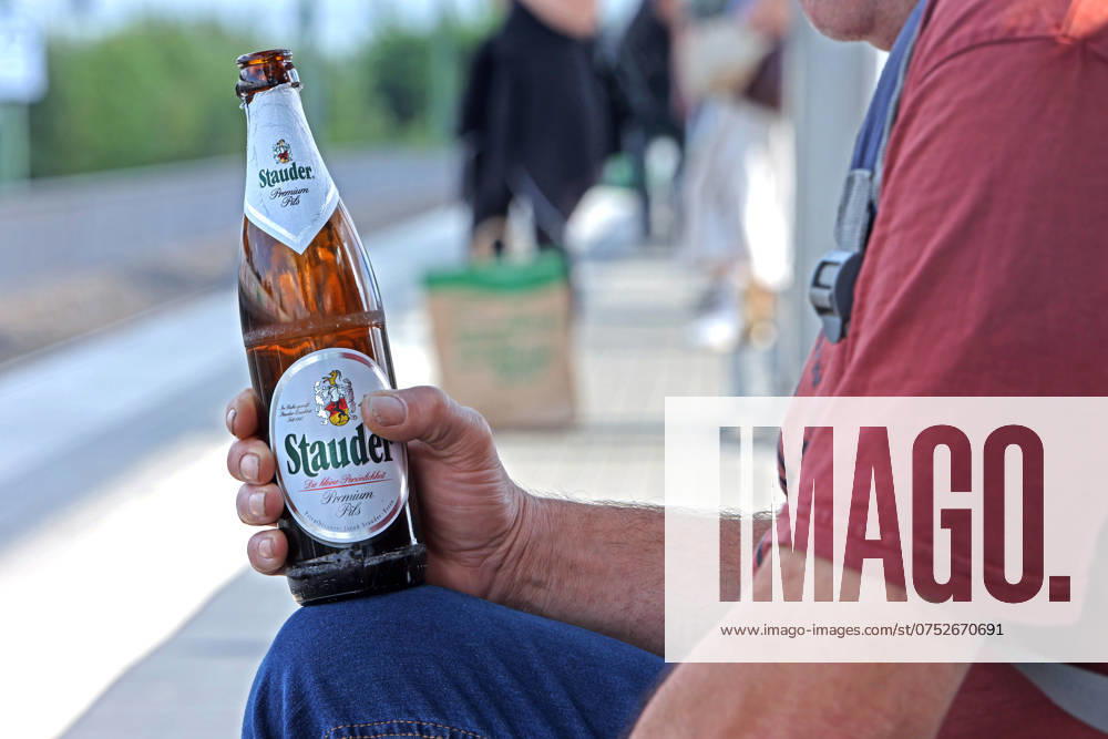Wasted time A man holds his after-work beer in his hand and waits for a train that never comes
