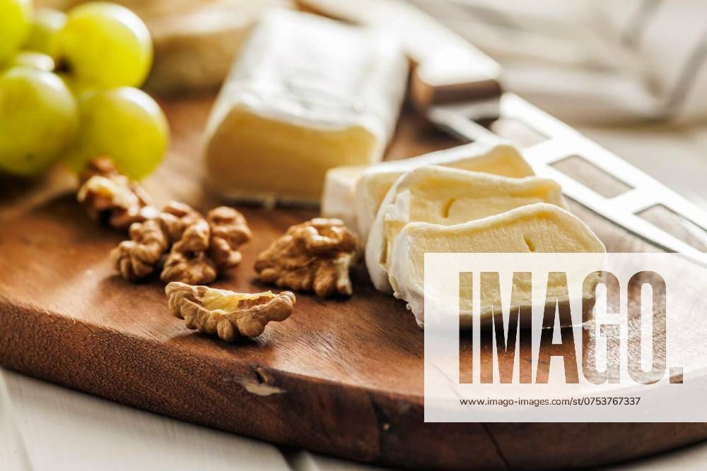 Sliced Brie cheese on a wooden board, Artisan Brie cheese sliced on a round wooden cutting board, served with grapes and walnuts, ideal image for Gourmet cheese concepts, Artisan Brie cheese sliced on a round wooden cutting board, served with grapes and walnuts, ideal image for Gourmet cheese concepts, 14.03.2024,