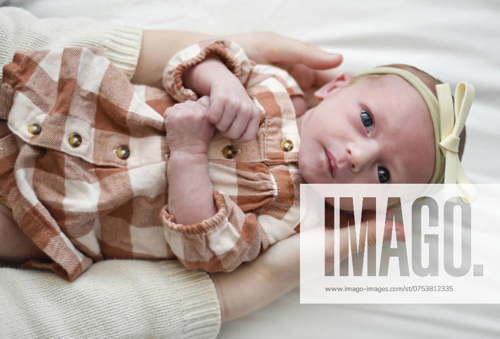 Newborn baby in a peach checkered outfit with a yellow bow head United States, Florida, Inverness R_YWQX240808D-1508066-01 ,model released, Symbolfoto