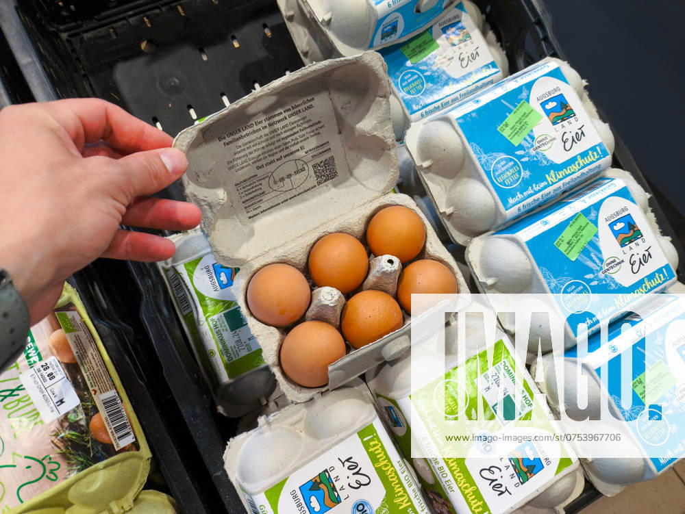 A customer opens an egg carton in the supermarket to check the freshness and quality of the eggs before buying
