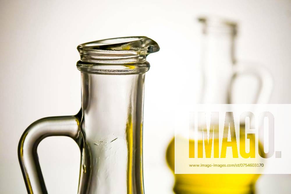 Two glass bottles filled with olive oil, placed side by side on a reflective surface, against white background and studio light., Two glass bottles filled with olive oil, placed side by side on a reflective surface, against white background and studio light., Two glass bottles filled with olive oil, placed side by side on a reflective surface, against white background and studio light., 05.07.2024,