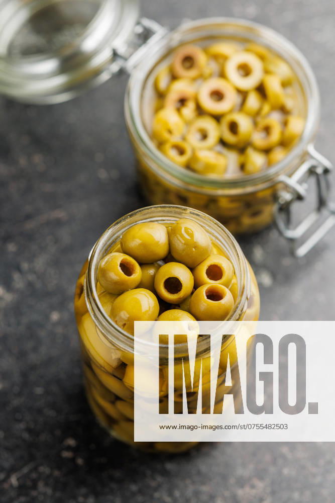 Pickled green olives in brine on black table. Pickled green olives in brine on a black table.