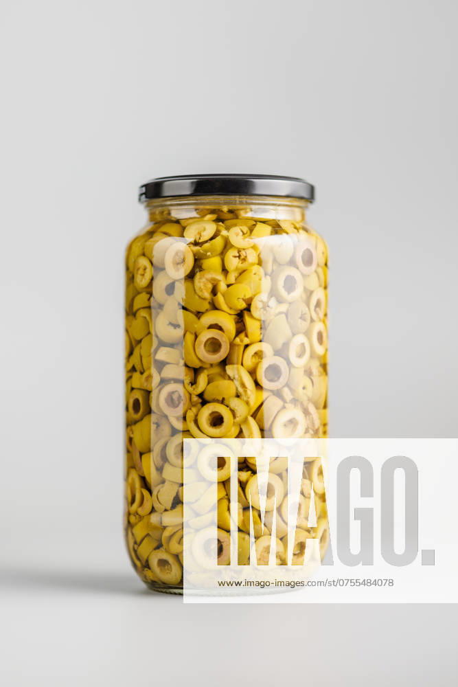Sliced pickled green olives in brine in jar on gray background. Sliced pickled green olives in brine in jar on a gray background.