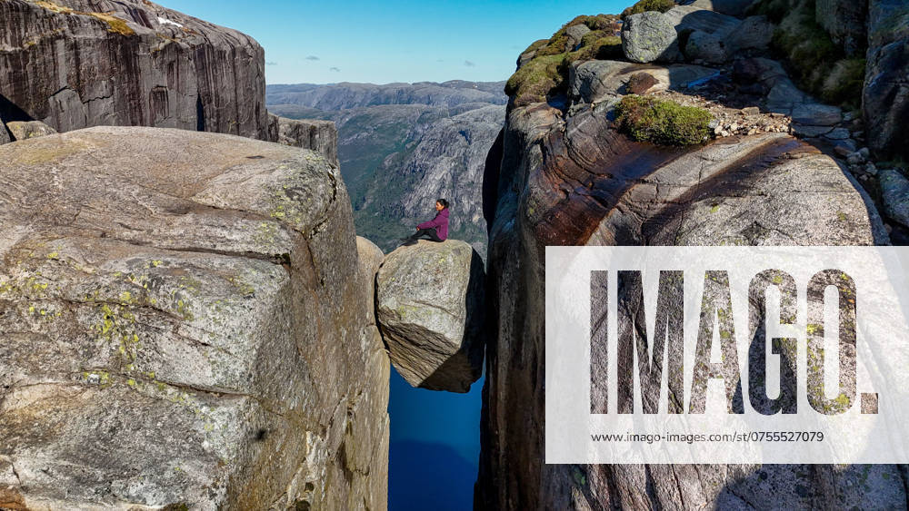 Adventurous Soul Balancing on Rock in Norway s Stunning Lysefjord A daring individual perches on a precarious boulder that precariously teeters between towering cliffs, surrounded by breathtaking fjord views. Kjerag Kjeragbolten Lysefjord Norway ,model released, Symbolfoto