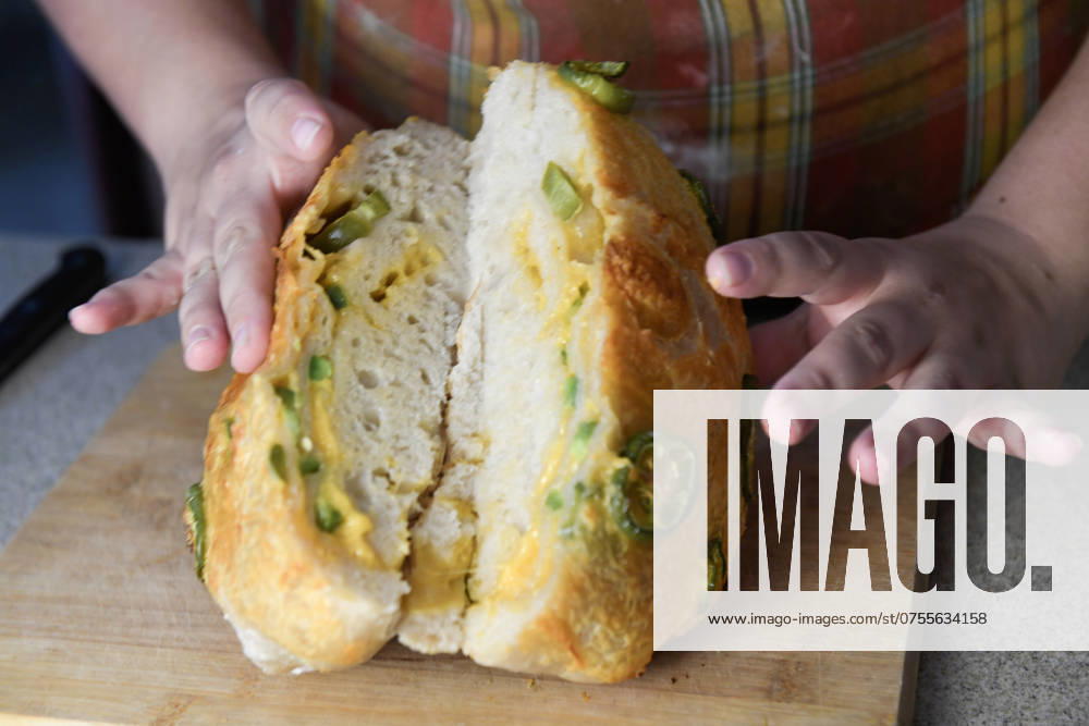 Hands holding a sliced jalapeno-topped bread loaf, showing the United States, Florida, Inverness R_YWQX240805A8-1499218-01 ,model released, Symbolfoto