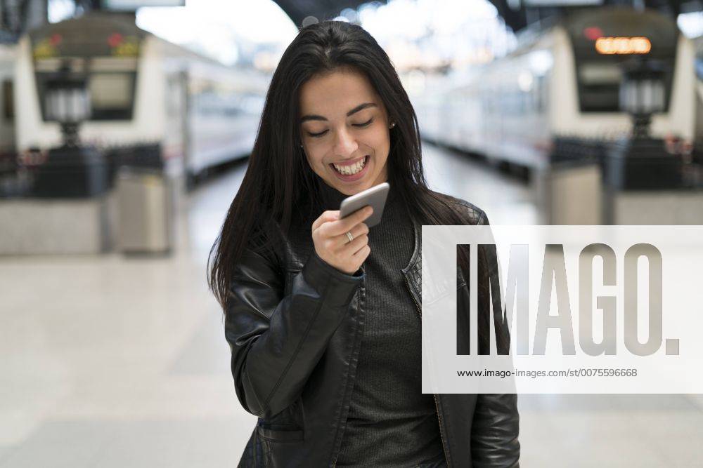 Happy young woman with cell phone at train station model released Symbolfoto KKAF00187