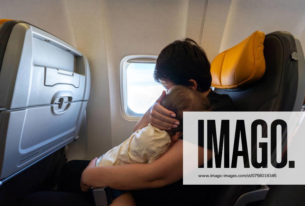 Loving mother holding her precious baby by airplane window during flight. Concept of travel and family bonding Loving mother holding her precious baby while seated by the airplane window during their flight. Concept of travel, family bonding, and the joy of shared moments ,model released, Symbolfoto