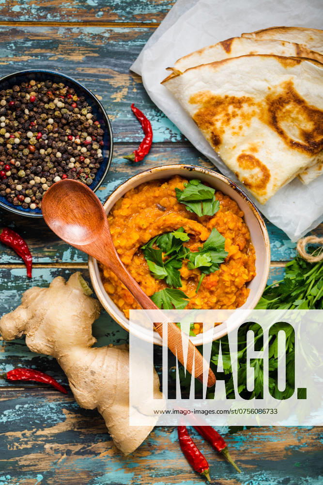 Traditionelle indische Linsen Dal, Naan Butterbrot, frischer Koriander. Indische Dhal würzigen Curry in Schüssel, Gewürze, Kräuter, rustikalen hölzernen Hintergrund. Ansicht von oben. Indisches Essen. Authentisches indisches Gericht. Draufsicht Traditional Indian lentils Dal, naan butter bread, fresh coriander. Indian Dhal spicy curry in bowl, spices, herbs, rustic wooden background. Top view. Indian food. Authentic Indian dish. Overhead