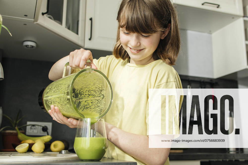 Girl pouring freshly made smoothie in glass at home model released, Symbolfoto property released, ELMF00675