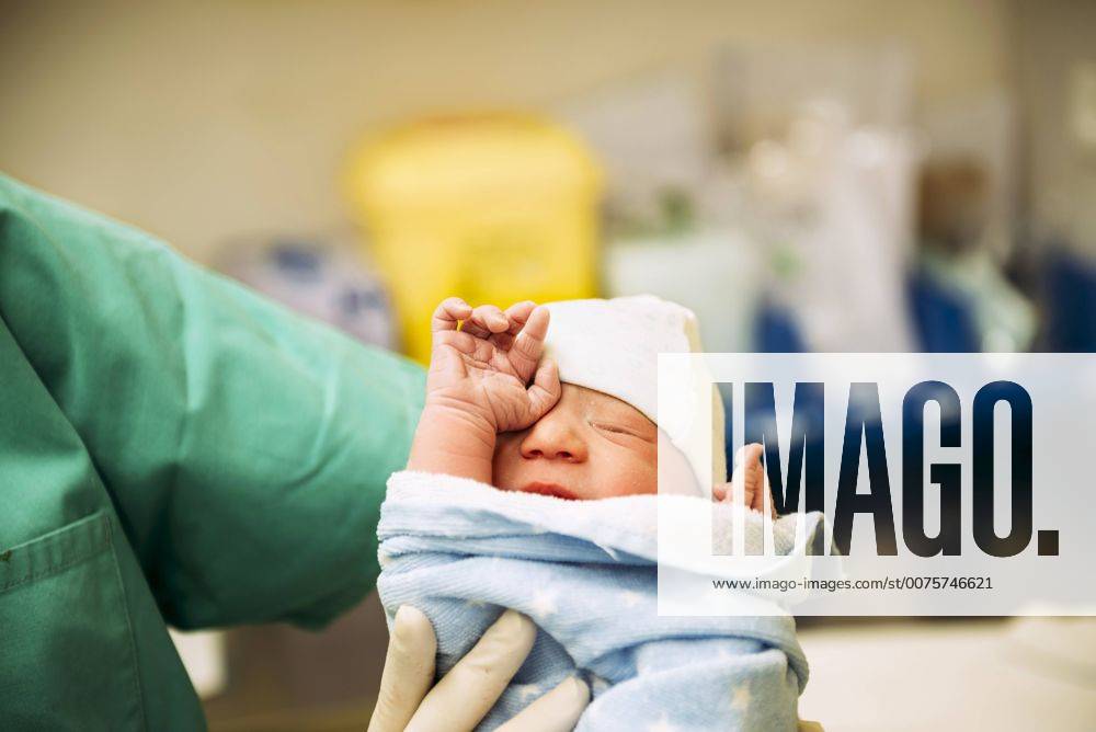 Newborn girl wrapped in a towel holded by the doctor in the delivery room model released Symbolfoto GEMF01301