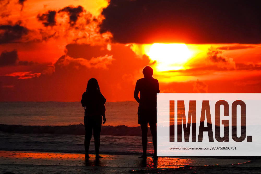 A couple silhouetted by the sunrise watch as the sun breaks out under a storm cloud at the start of the Labor Day weekend on the beach, August 31, 2024 in Isle of Palms, South Carolina. Isle Of Palms United States - ZUMAe02_ 20240831_zaf_e02_007