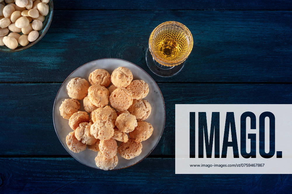 Amaretti, traditionelles italienisches Mandelgebäck, mit einem Glas Amaretto Likör, Aufnahme von oben mit Platz für Text auf dunkelblauem Holzhintergrund Amaretti, traditional Italian almond cookies, with a glass of Amaretto liqueur, shot from the top with a place for text on a dark blue wooden background