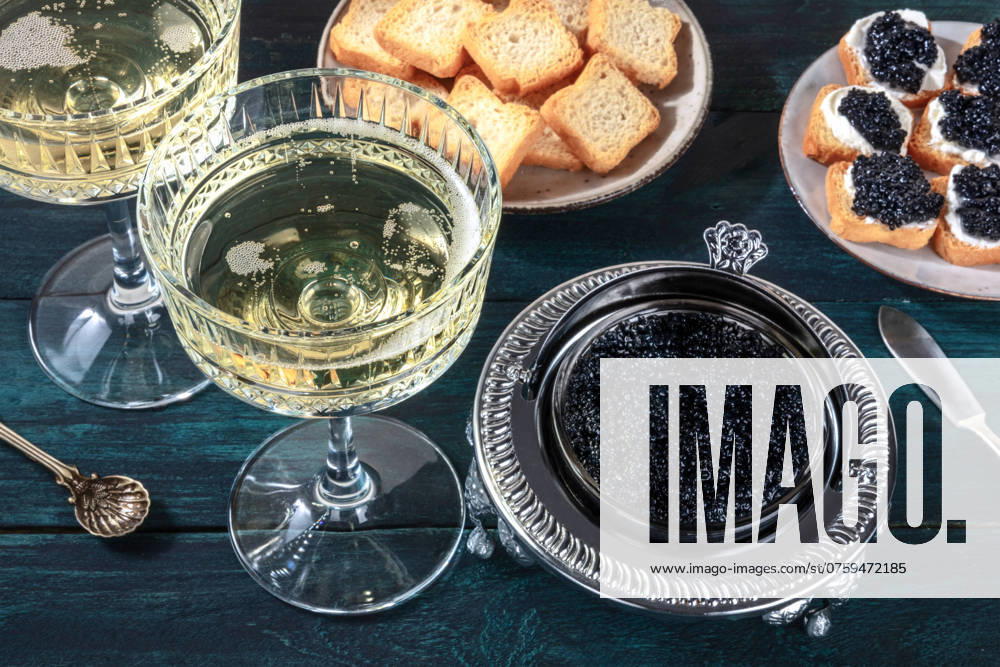 Kaviar und Champagner, Vintagestil mit Brot und Toast auf einem dunkelblauen hölzernen Hintergrund Caviar and champagne, vintage style, with bread and toasts on a dark blue wooden background
