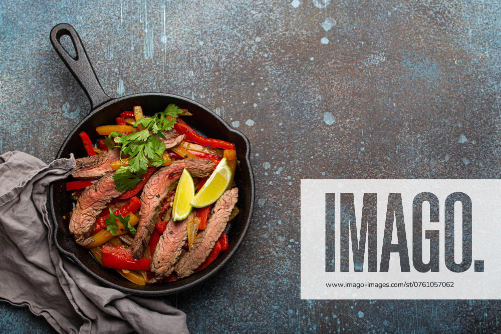 IMAGO Creative, Food, Fajita Traditionelles mexikanisches Gericht Rindfleisch Fajitas mit Paprika in schwarzem Gusseisen Pfanne auf rustikalen Stein Hintergrund von oben mit Platz für Text, American Mexican Food Traditional Mexican dish Beef fajitas with bell peppers in black cast iron pan on rustic stone background from above with space for text, American Mexican food