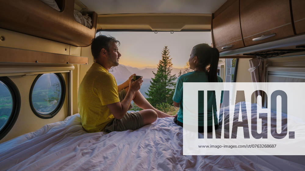 Enjoying a serene sunrise view from a camper van in Hallstatt, Austria with loved ones Nestled in a cozy camper van, a couple shares a peaceful moment while watching the sunrise over the breathtaking landscape of Hallstatt, Austria, surrounded by nature s beauty. Loserhutte mountain ,model released, Symbolfoto