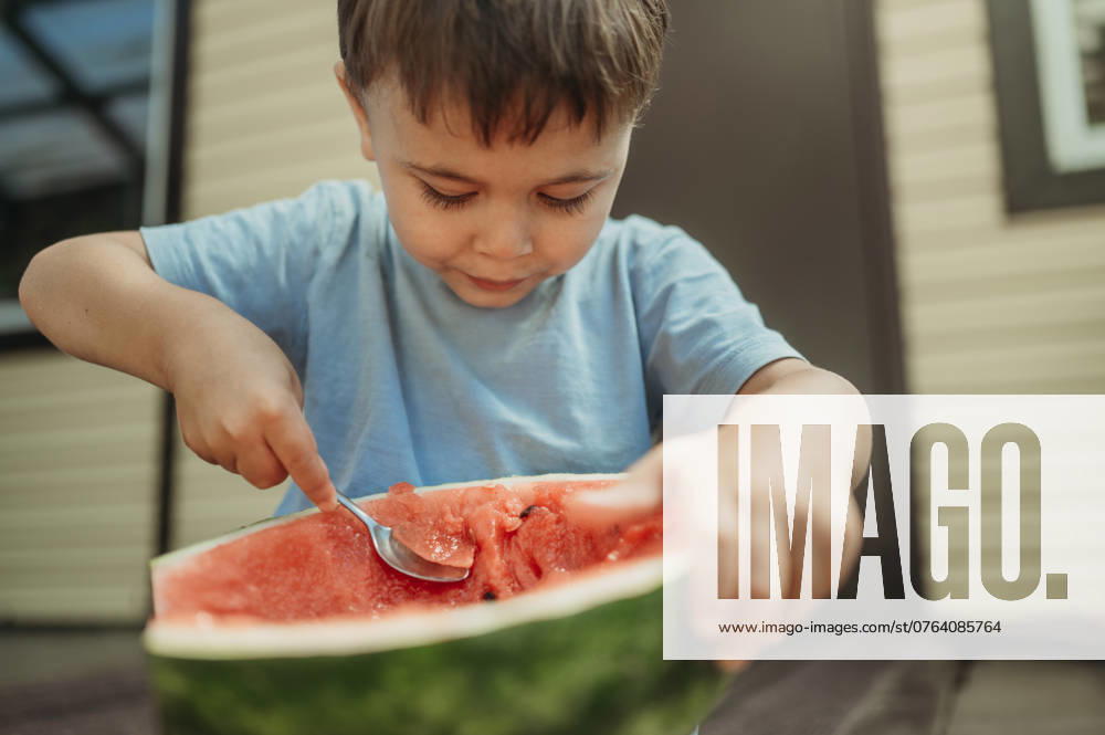 Cute boy eating watermelon with spoon in back yard model released, Symbolfoto, ANAF03630