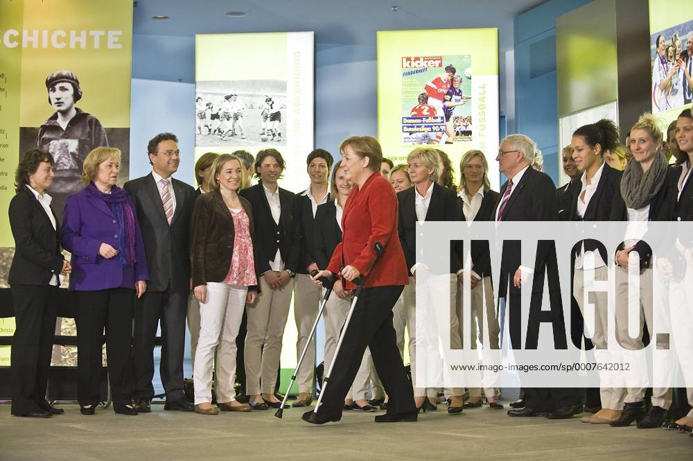 Bundeskanzlerin Angela MERKEL (CDU) auf Krücken sowie, v.li. Co Trainerin Ulrike BALLWEG, Maria BÖHMER (CDU Beauftragte der Bundesregierung für Migration), Innenminister Hans Peter FRIEDRICH (CSU) und Familienministerin Kristina SCHRÖDER (CDU); außerdem: Trainerin Silvia NEID (Mitte), DFB Präsident Theo ZWANZIGER, Celia OKOYINO DA MBABI und Anja MITTAG, --- Eröffnung der Ausstellung FRAUEN SCHREIBEN FUSSBALGESCHICHTE im Bundeskanzleramt Berlin o0 Verletzung Nationaltrainer