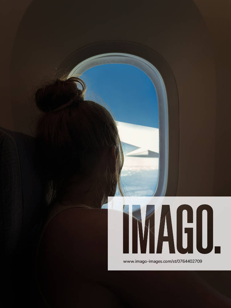 Side view of unrecognizable person looking out airplane window, holding Spanish passport, depicting travel and flight. Model Released Javigu_ID23944_694493_004