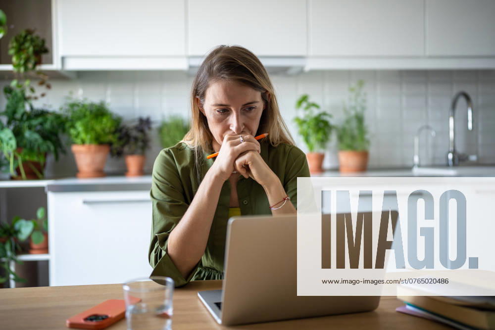 Focused thoughtful woman with laptop deep in process of solving tasks problems remote work IT field. Focused IT woman working at home with laptop. Carried by job process, freelancer concentrate on solving tasks problems, forgot about time rest. Worried woman perplexed looking at screen computer. ,model released, Symbolfoto