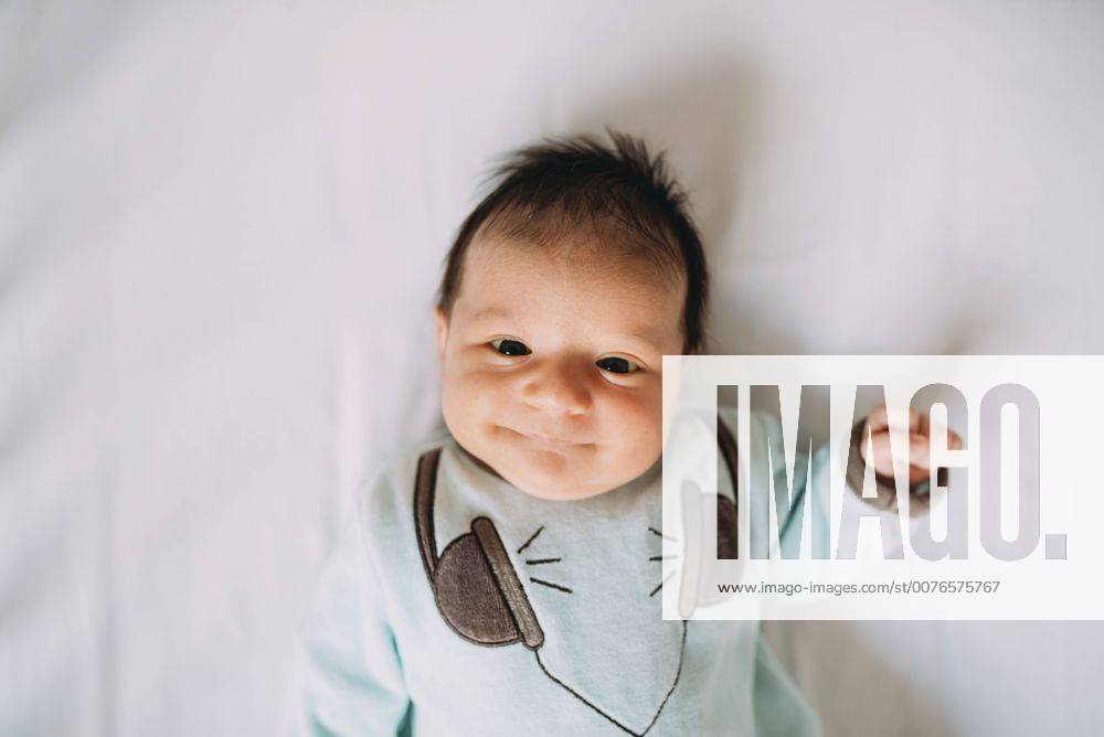 Happy newborn baby girl lying on bed model released Symbolfoto GEMF01389