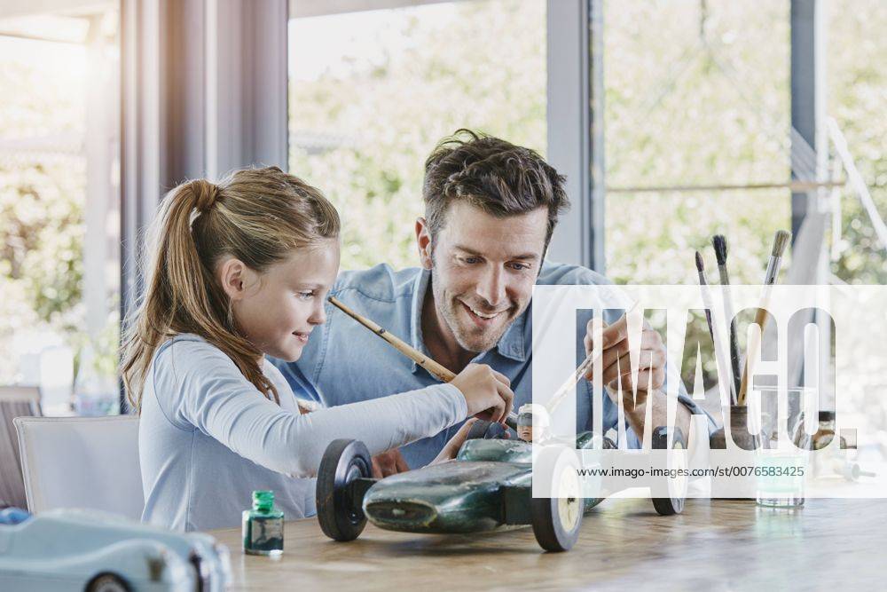 Father and daughter painting a toy race car model released Symbolfoto property released RORF00479