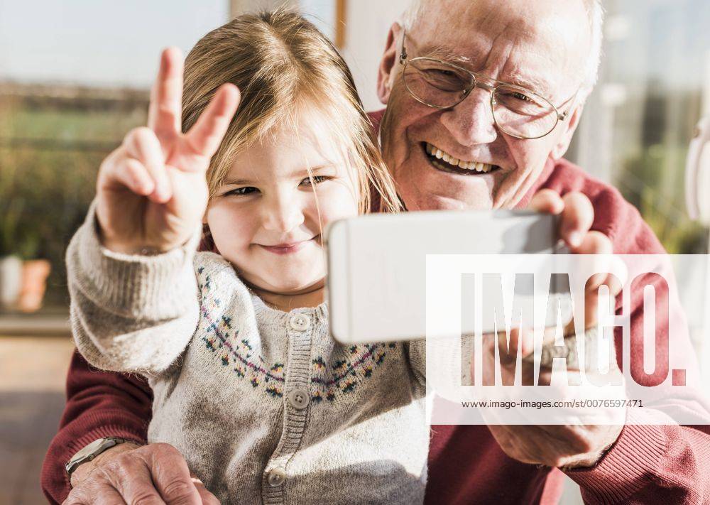 Grandfather and granddaughter taking selfies with a smart phone model released Symbolfoto property released UUF09547