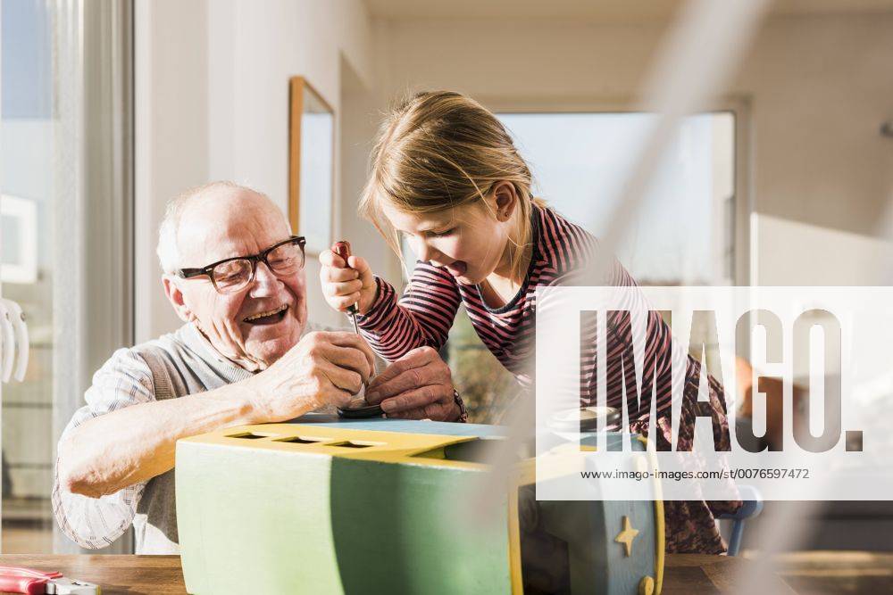 Grandfather and granddaughter assembling toy bus model released Symbolfoto property released UUF09548