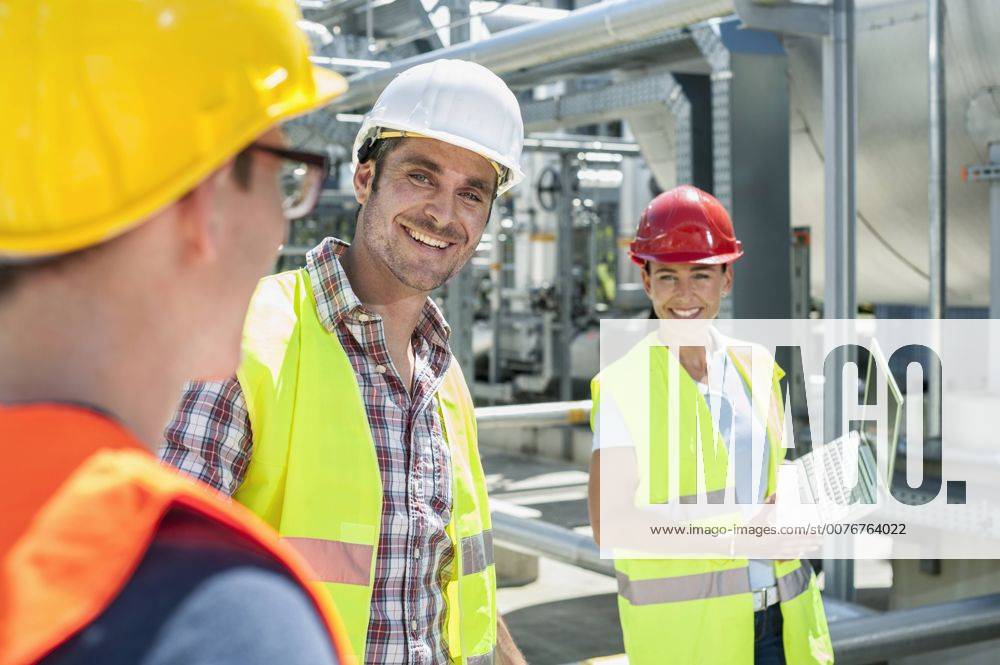 IMAGO Creative: Gesellschaft, Integration Happy engineer with his colleagues in meeting with laptop at geothermal power station, Bavaria, Germany mit_2003_10286