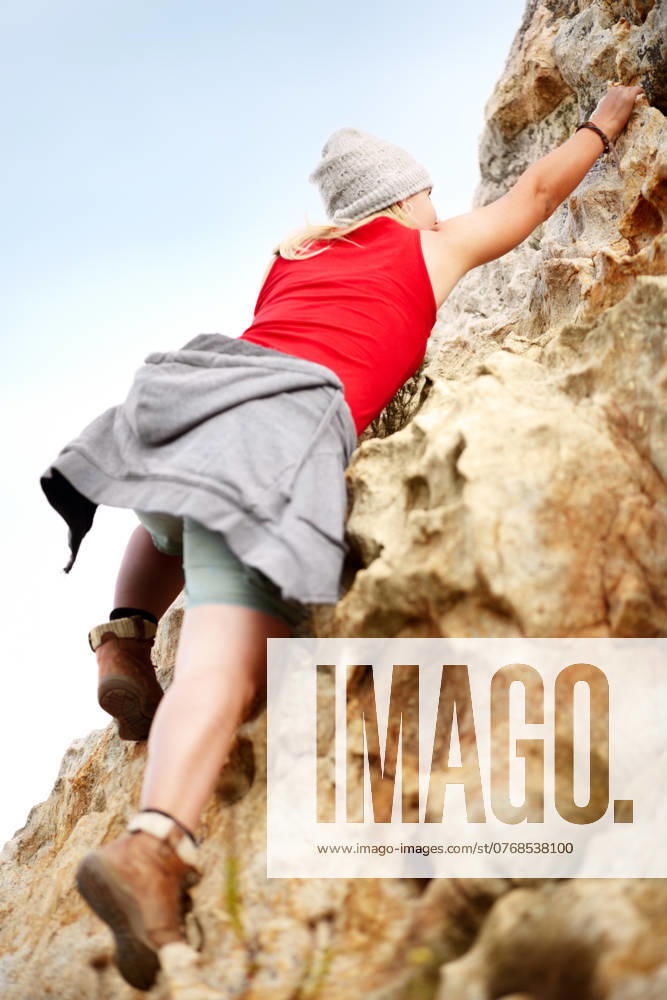 Woman on cliff, rock climbing and hiking adventure in mountain with nature, freedom and power. Travel, girl trekking and hanging, strong person in countryside on natural outdoor journey with fitness model released property released