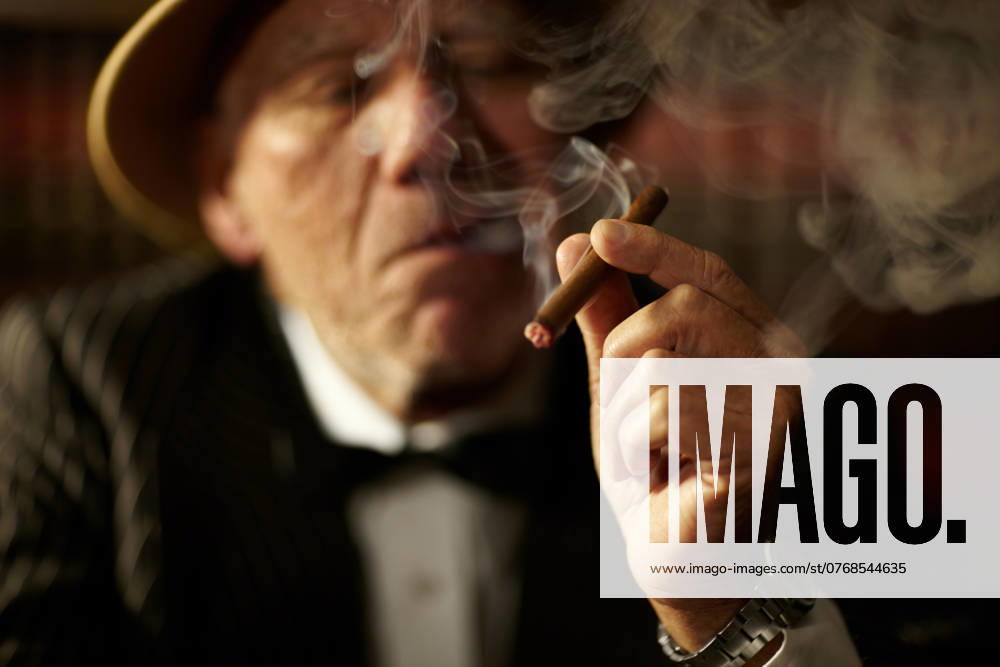 Old man, smoking and cigarette in hand with smoke and crime boss of mob with a decision. Gangster, face and senior person with vintage cigar in mafia or country club with luxury, vice or habit. model released property released